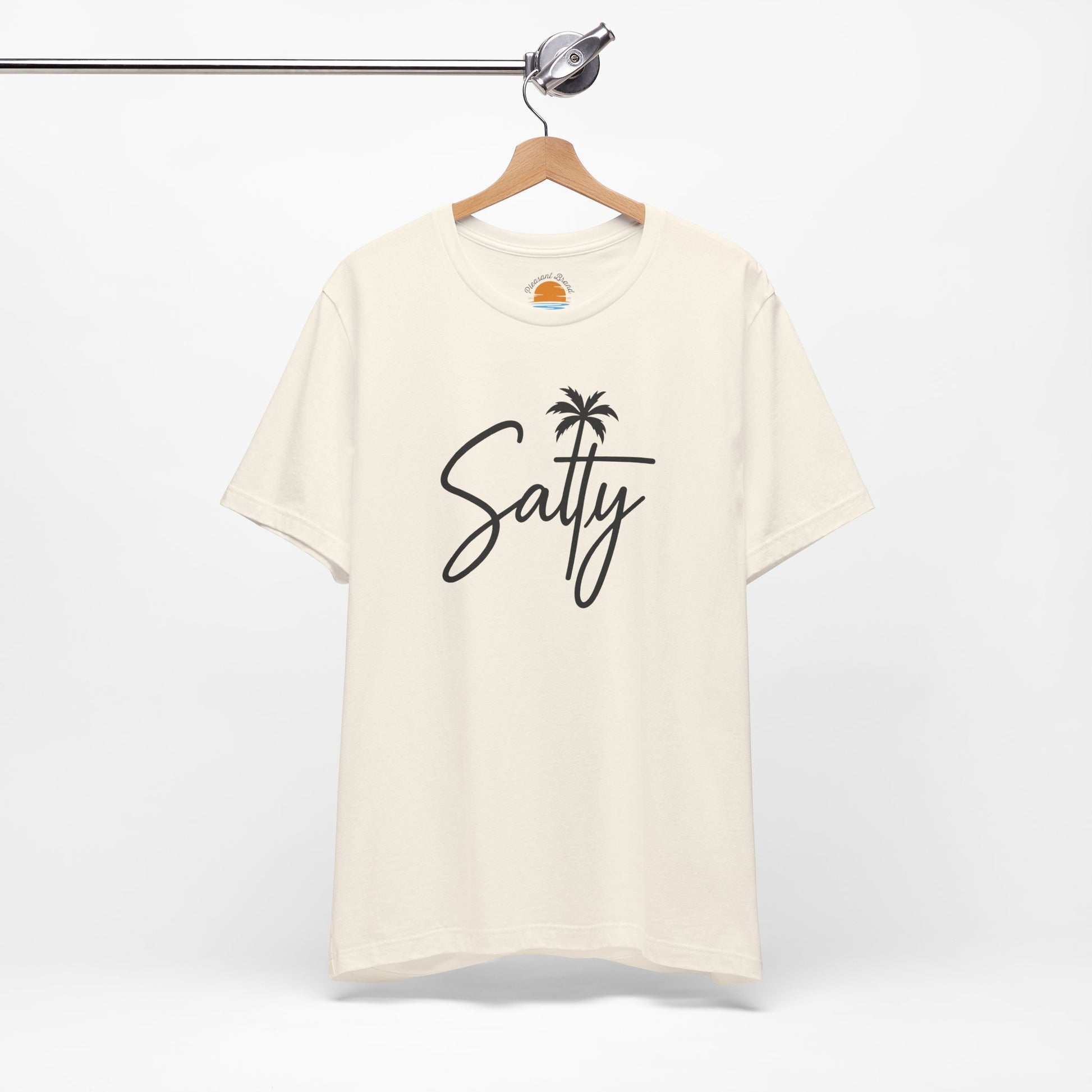 Beige t-shirt with 'Salty' and a palm tree design on a hanger against a white background