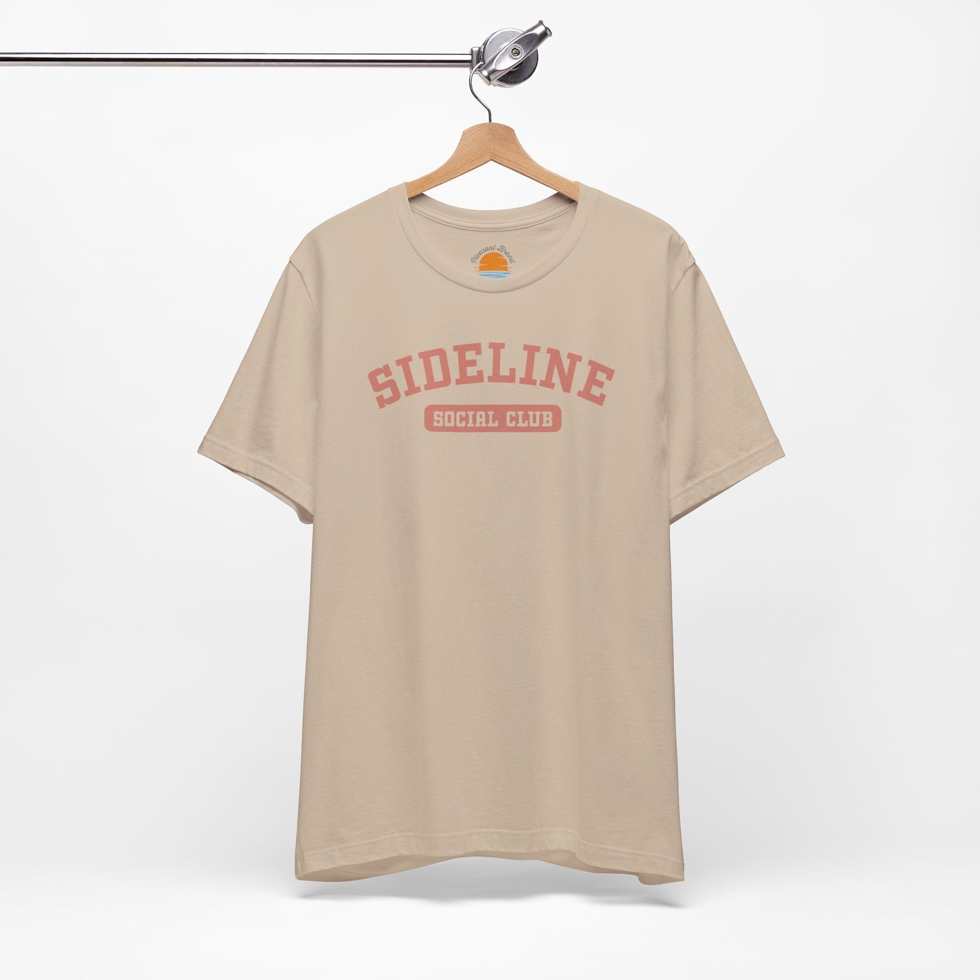 Tan t-shirt with 'Sideline Social Club' text on a hanger against a white background
