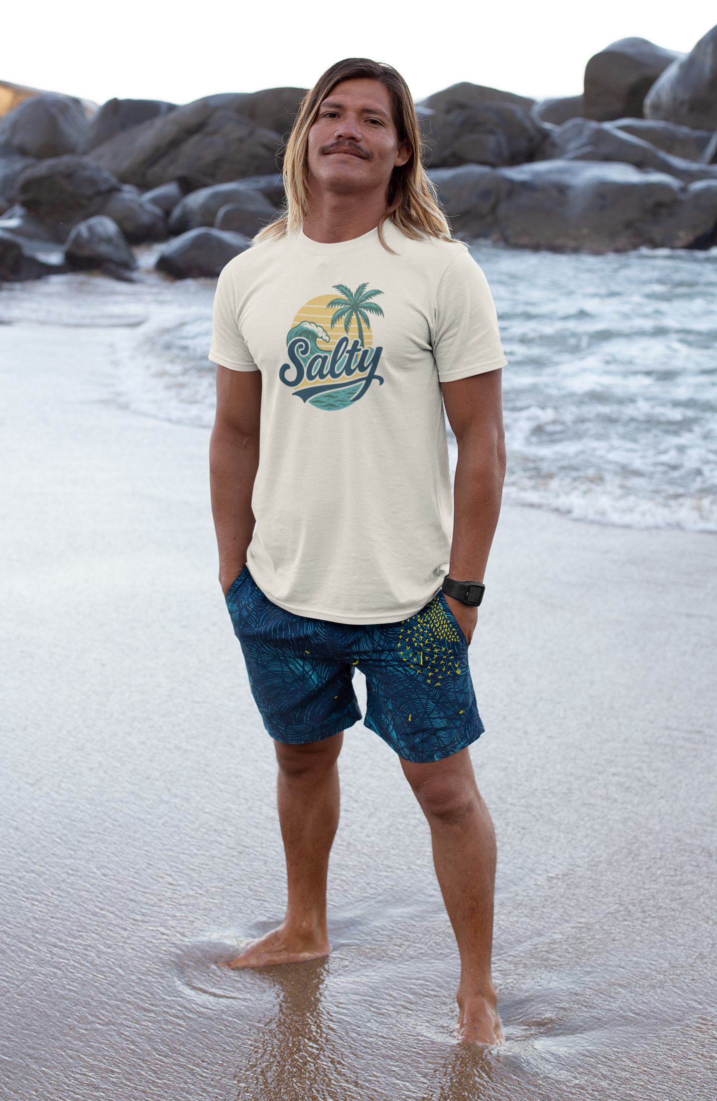 Man in Salty Tropical Sun T-Shirt with a palm tree design walking on beach at golden hour