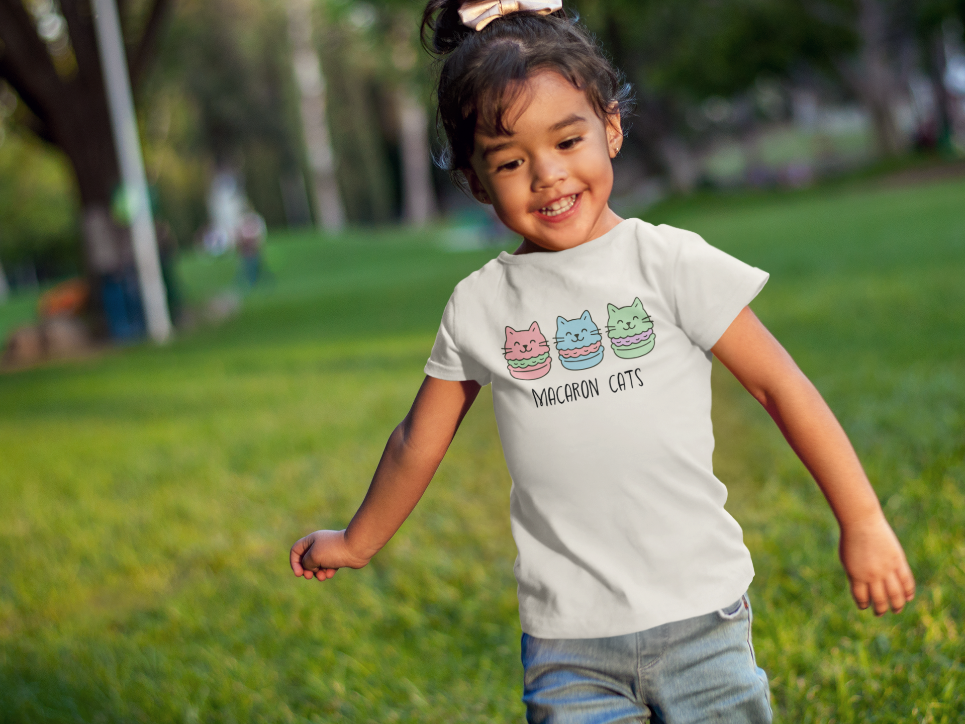 Happy toddler wearing Macaron Cats T-Shirt with arms spread wide showing pure joy in outdoor setting