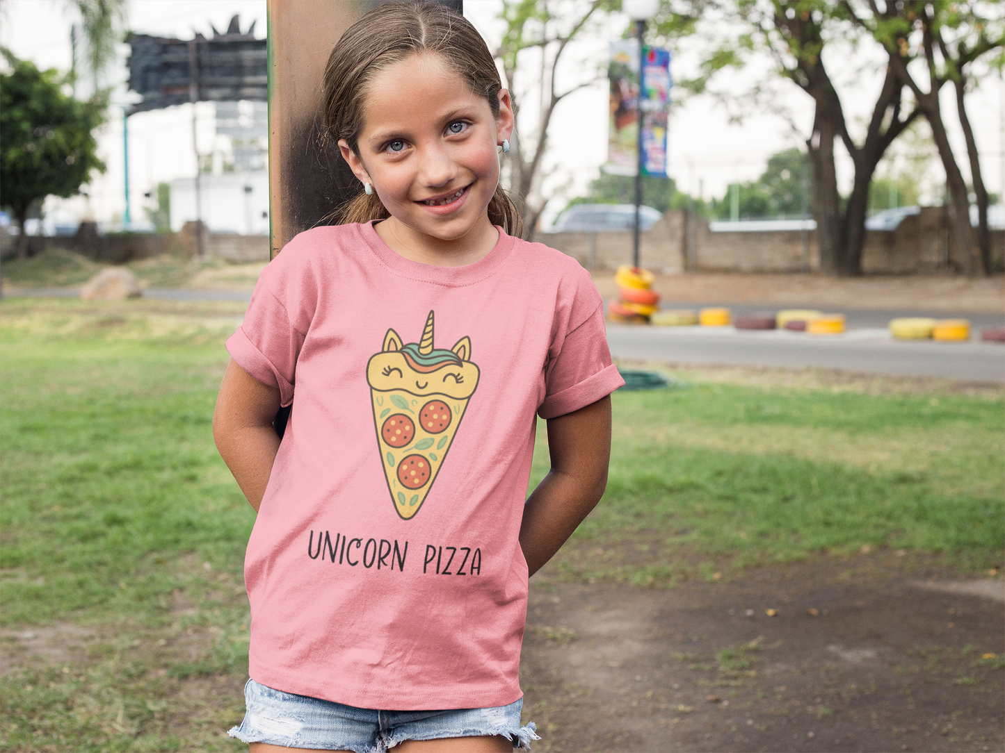 Happy young girl wearing pink Unicorn Pizza Youth T-Shirt with big smile at playground