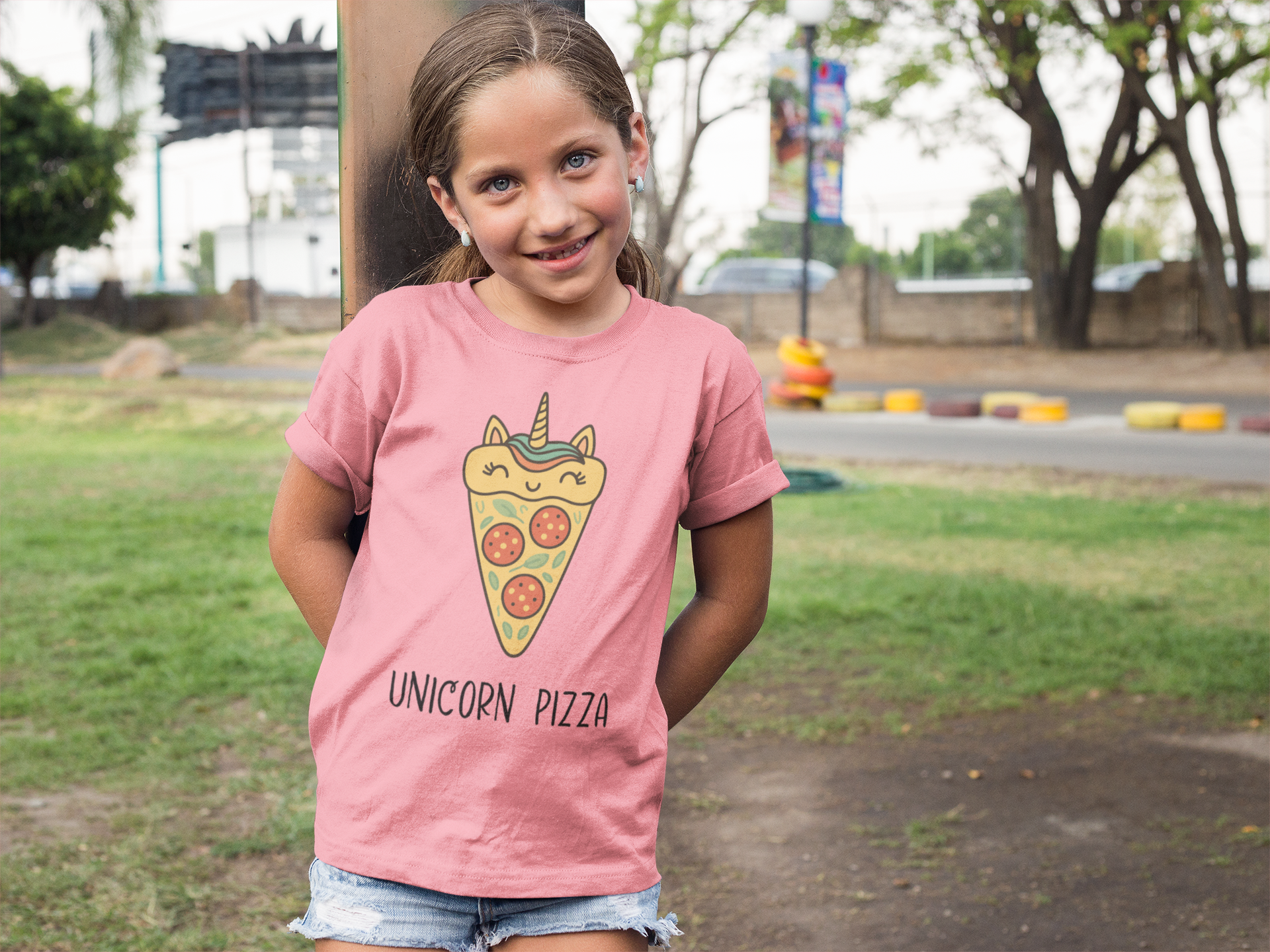 Happy young girl wearing pink Unicorn Pizza Youth T-Shirt with big smile at playground