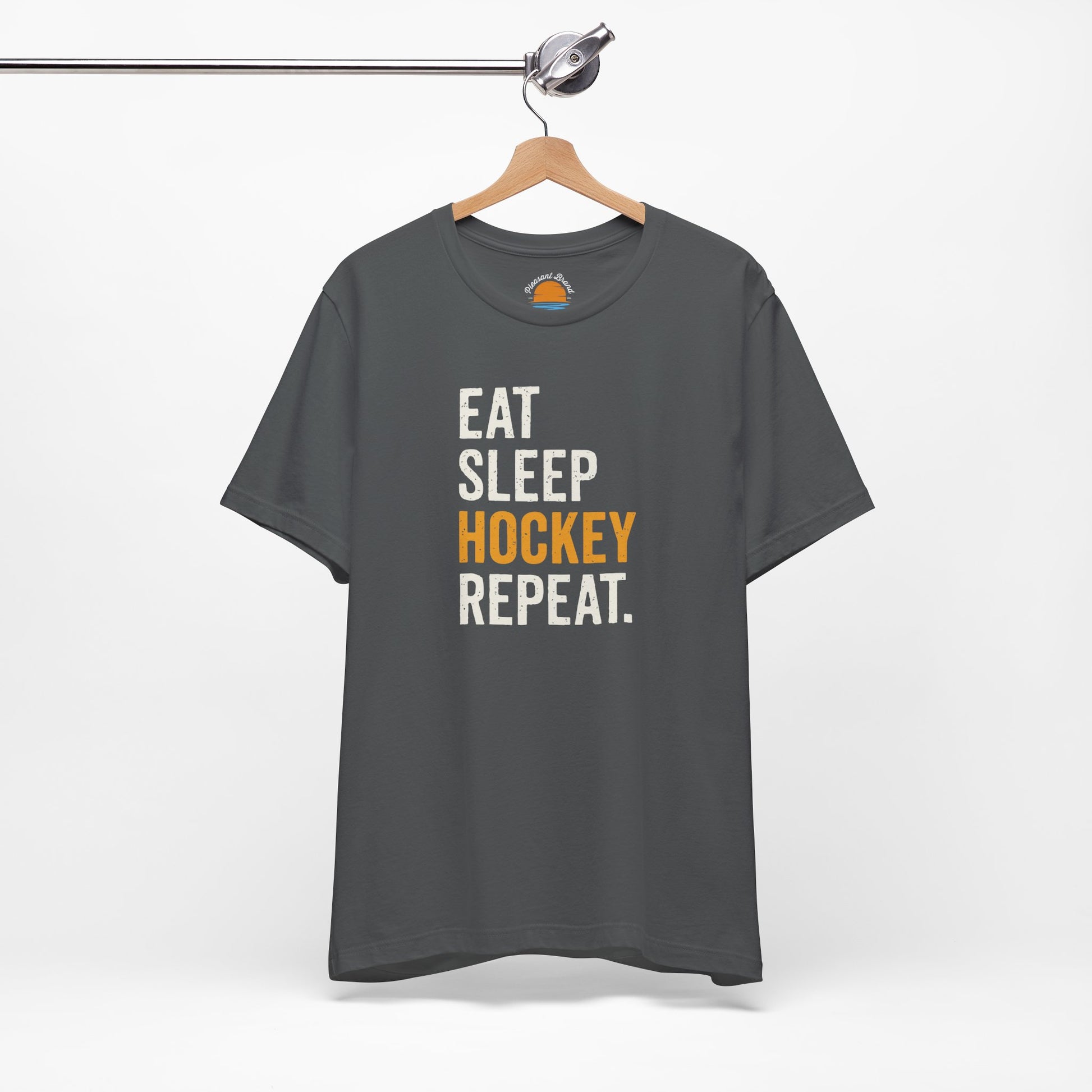 Asphalt t-shirt with 'Eat Sleep Hockey Repeat' text on a hanger against a white background