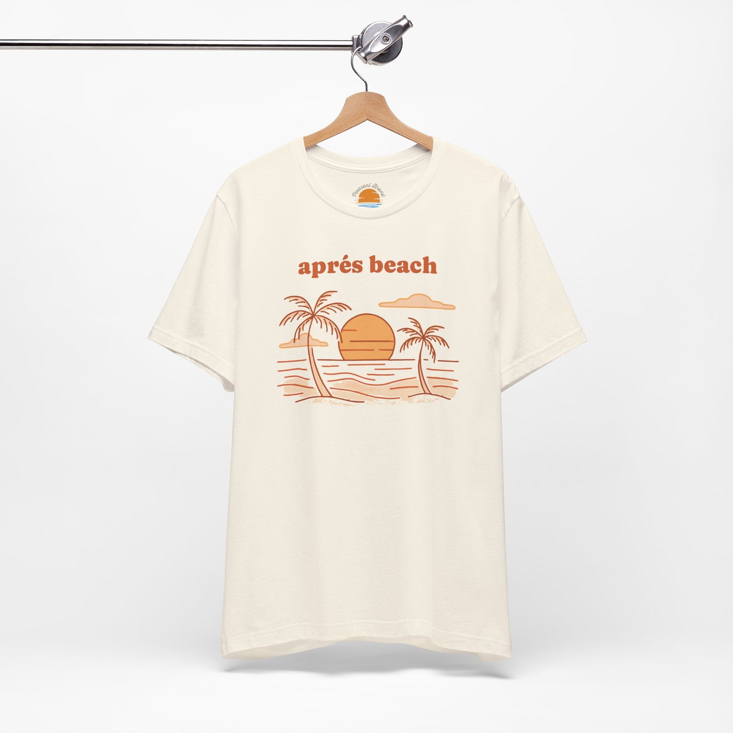 Natural color t-shirt with 'après beach' sunset and palm trees graphic design on a hanger against a white background.