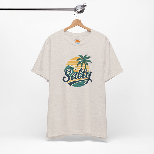 Beige t-shirt with 'Salty' graphic design featuring palm trees and a sunset on a hanger against a white background.