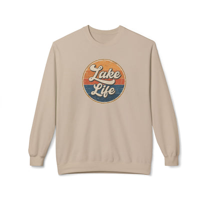 A beige crewneck sweatshirt featuring a circular retro-style graphic on the chest with the text 'Lake Life' in white script over orange and blue sunset stripes.