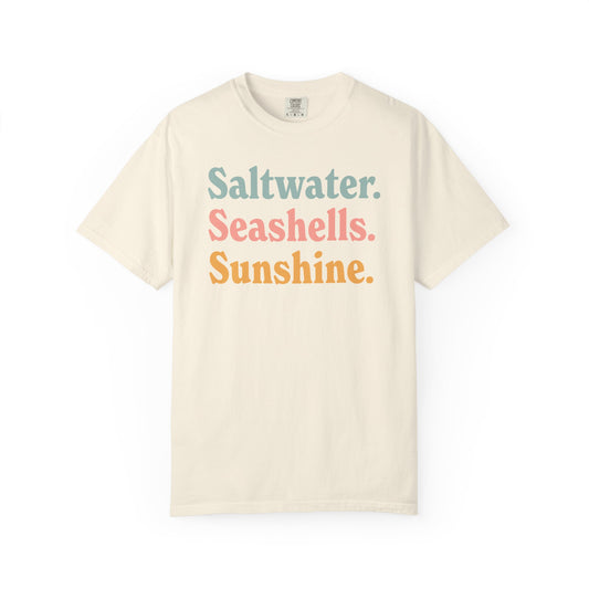 Ivory Comfort Colors t-shirt with colorful text 'Saltwater. Seashells. Sunshine.' on a white background