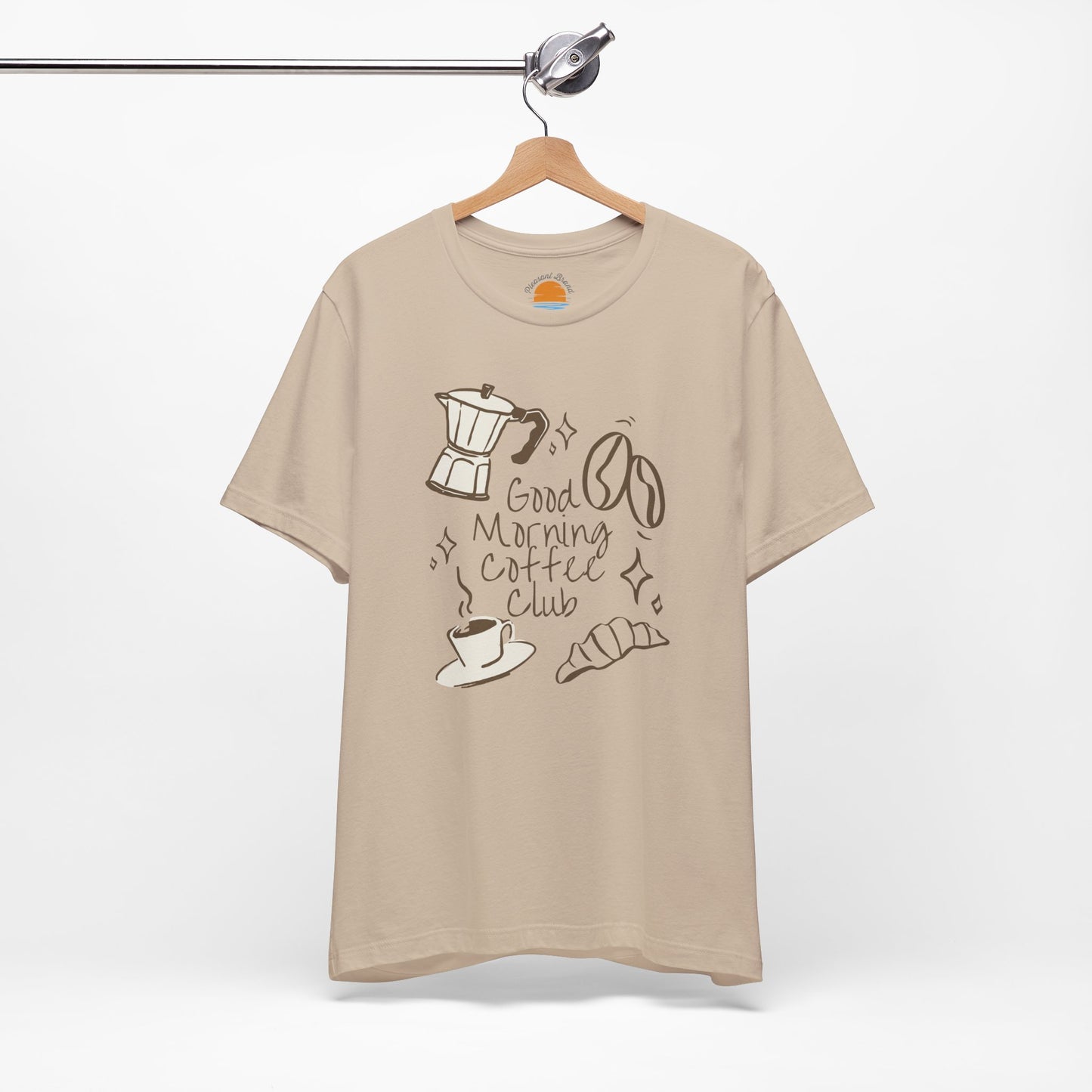 Beige t-shirt with coffee-themed design on a hanger against a white background