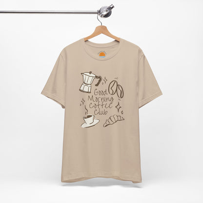 Beige t-shirt with coffee-themed design on a hanger against a white background