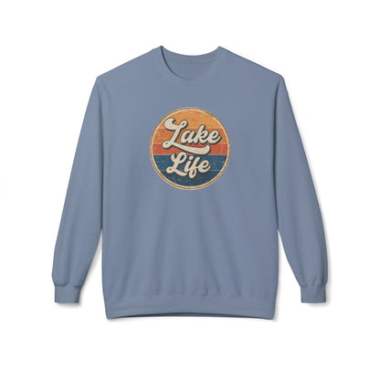 A dusty blue crewneck sweatshirt featuring a circular retro-style graphic on the chest with the words 'Lake Life' in white script over orange and navy blue stripes.