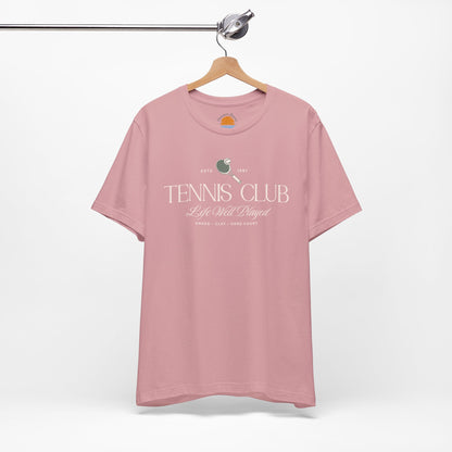 Pink t-shirt with 'Tennis Club' text and graphics on a hanger against a white background