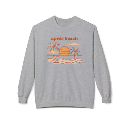 A heather gray crewneck sweatshirt featuring a retro beach graphic with the text 'après beach' in orange above a stylized illustration of palm trees, sand, and water.
