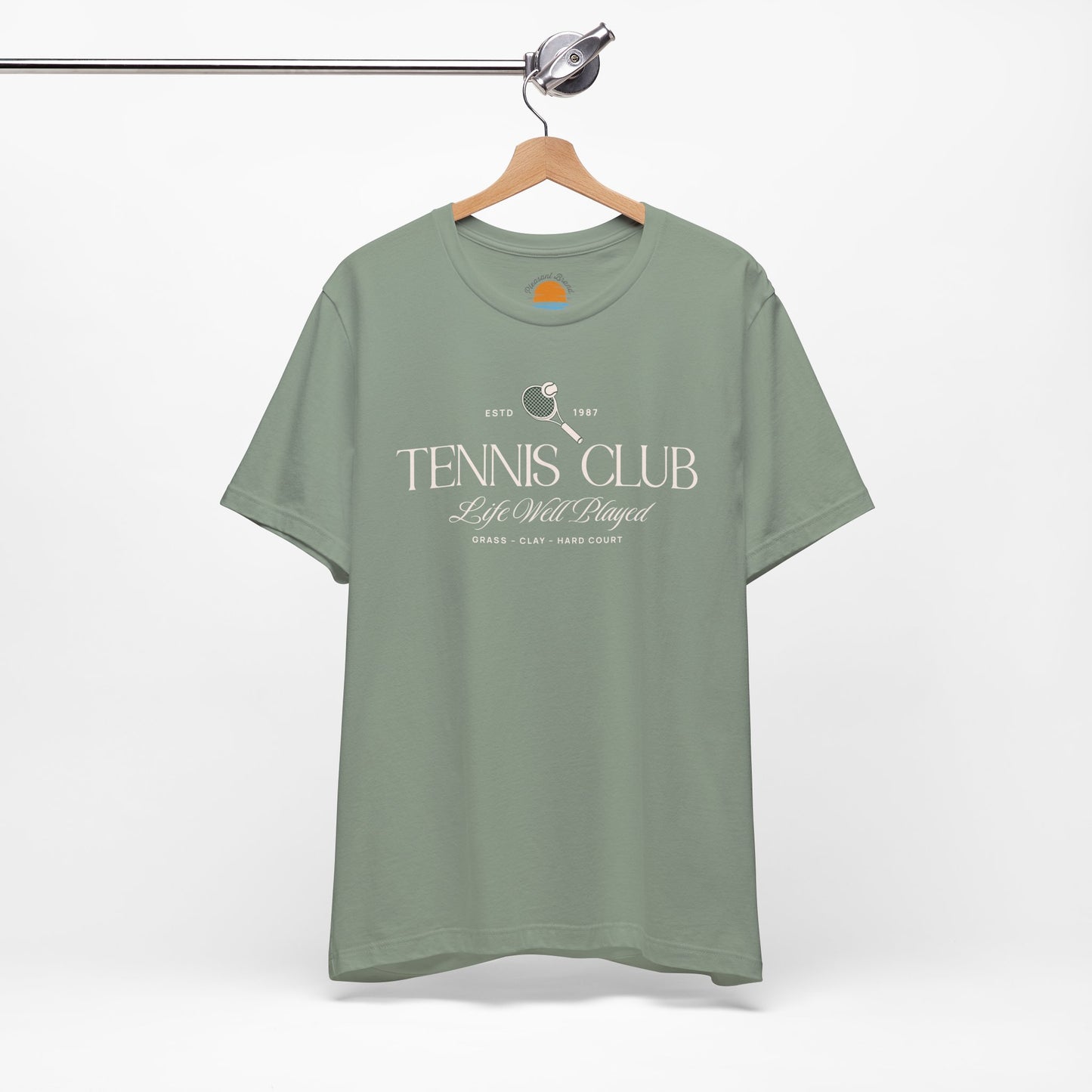 Green t-shirt with 'Tennis Club' text and graphics on a hanger against a white background.