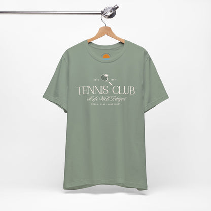 Green t-shirt with 'Tennis Club' text and graphics on a hanger against a white background.
