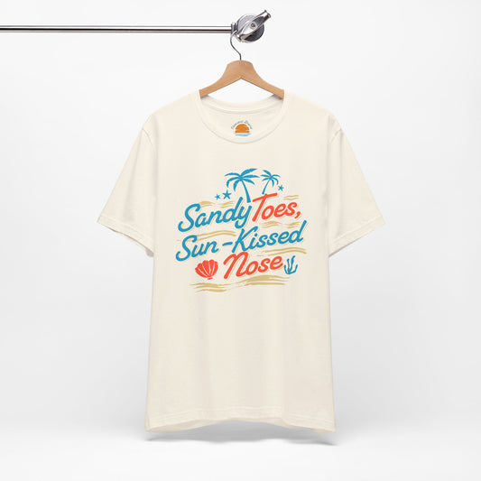Natural color t-shirt with 'Sandy Toes, Sun-Kissed Nose' text and graphics on a hanger against a white background