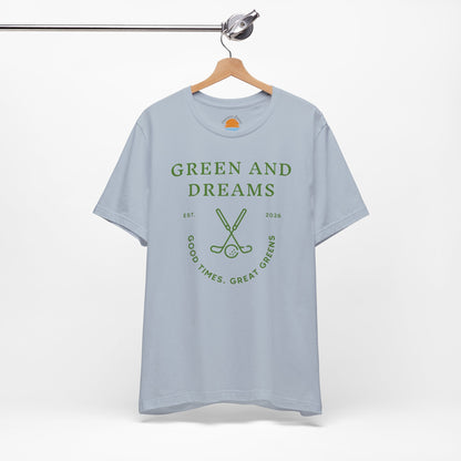 Light blue t-shirt with 'Green and Dreams' graphic design and text on a hanger against a white background
