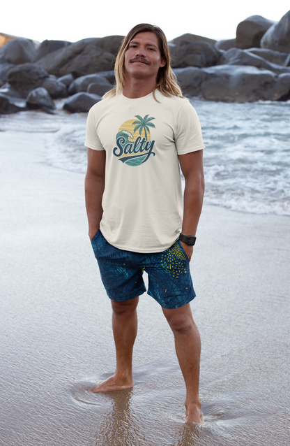 Man in Salty Tropical Sun T-Shirt with a palm tree design walking on beach at golden hour
