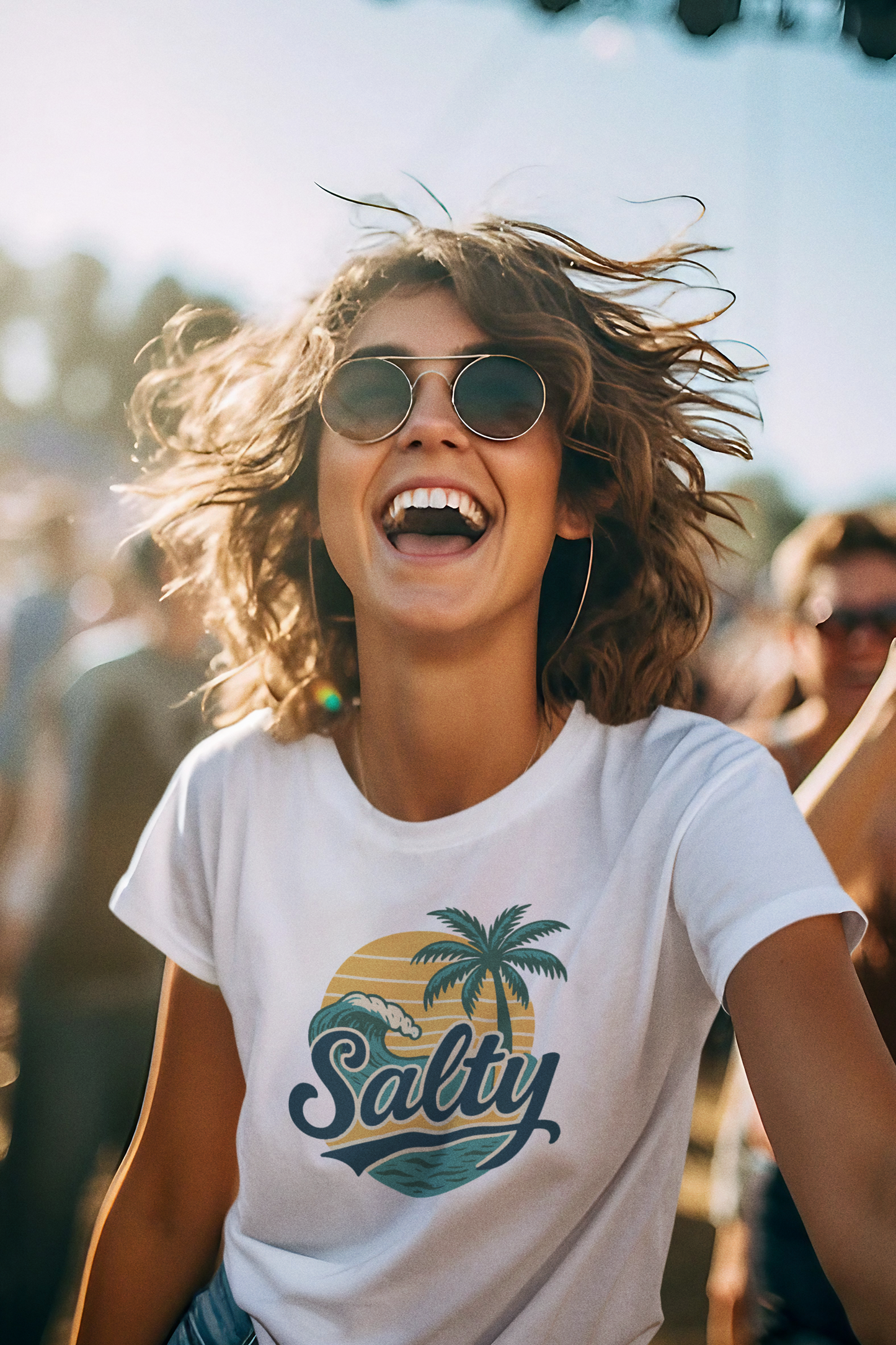 Woman laughing with joy wearing Salty Tropical Sun T-Shirt and sunglasses at beach festival