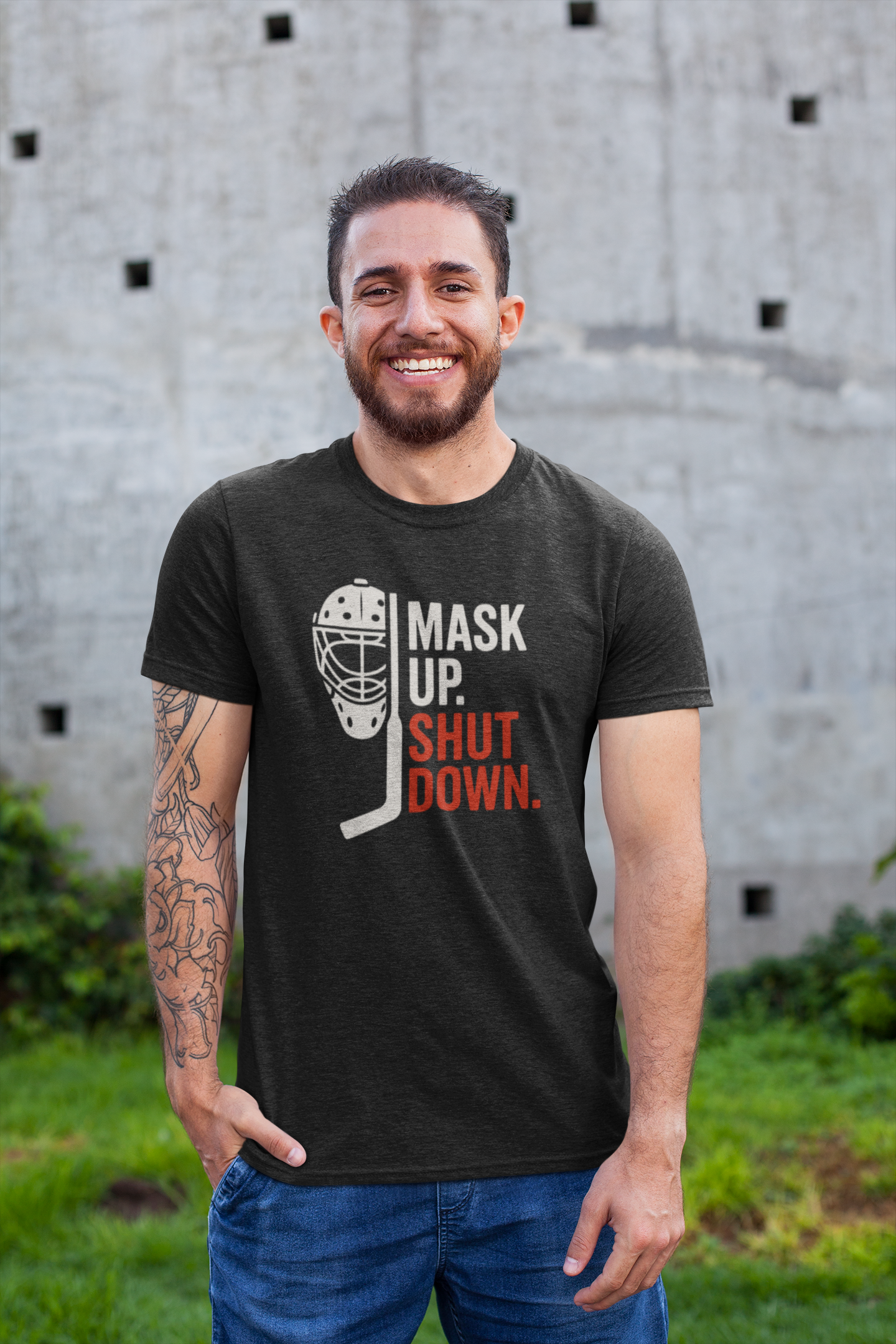 Confident man wearing Mask Up Shut Down T-Shirt with goalie mask design in casual outdoor setting