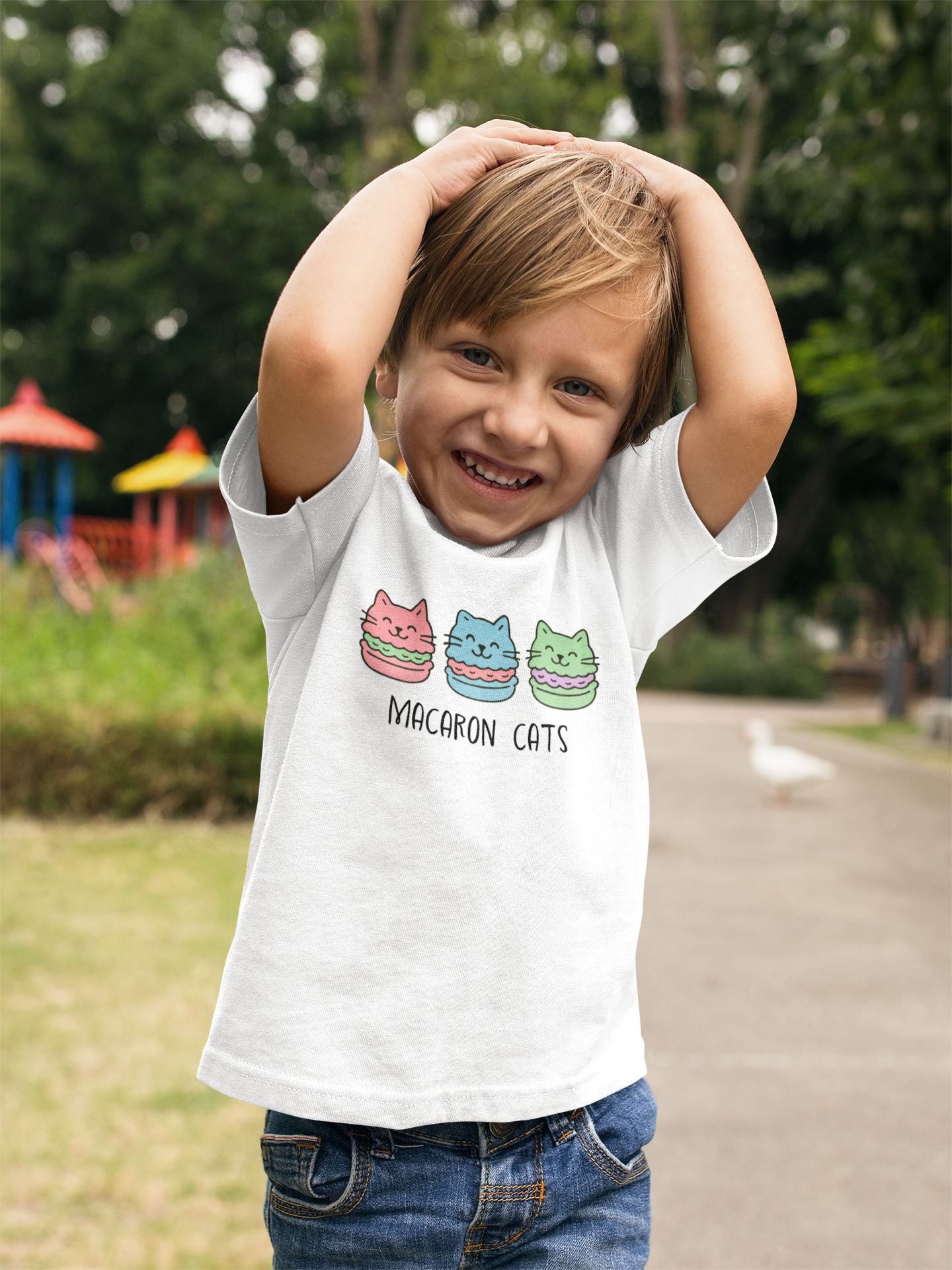 Playful child wearing Macaron Cats Toddler T-Shirt with hands behind head in carefree pose