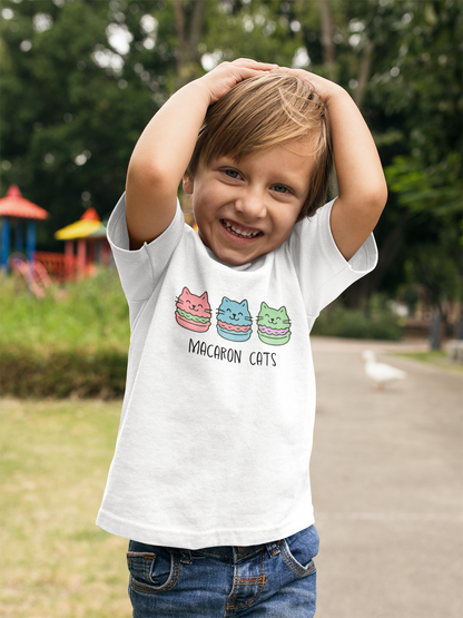 Playful child wearing Macaron Cats Toddler T-Shirt with hands behind head in carefree pose