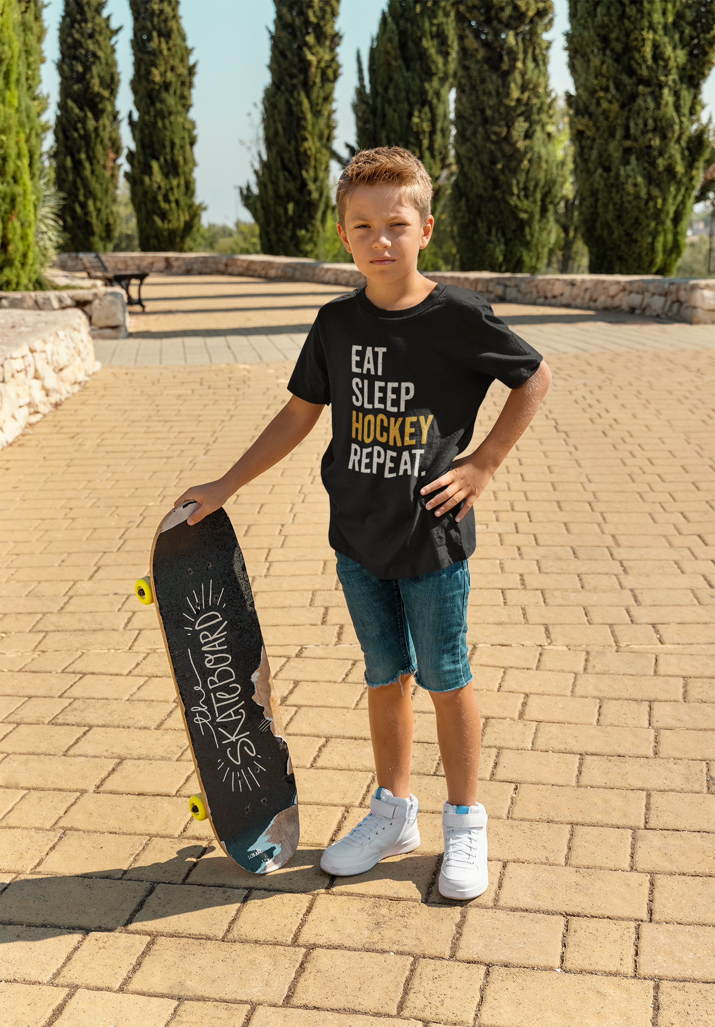 Cool kid in Eat Sleep Hockey Repeat Youth T-Shirt showing athletic confidence with skateboard