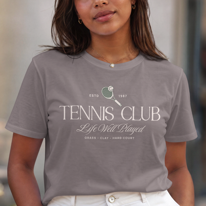 Person wearing a gray t-shirt with 'Tennis Club' text and graphics.