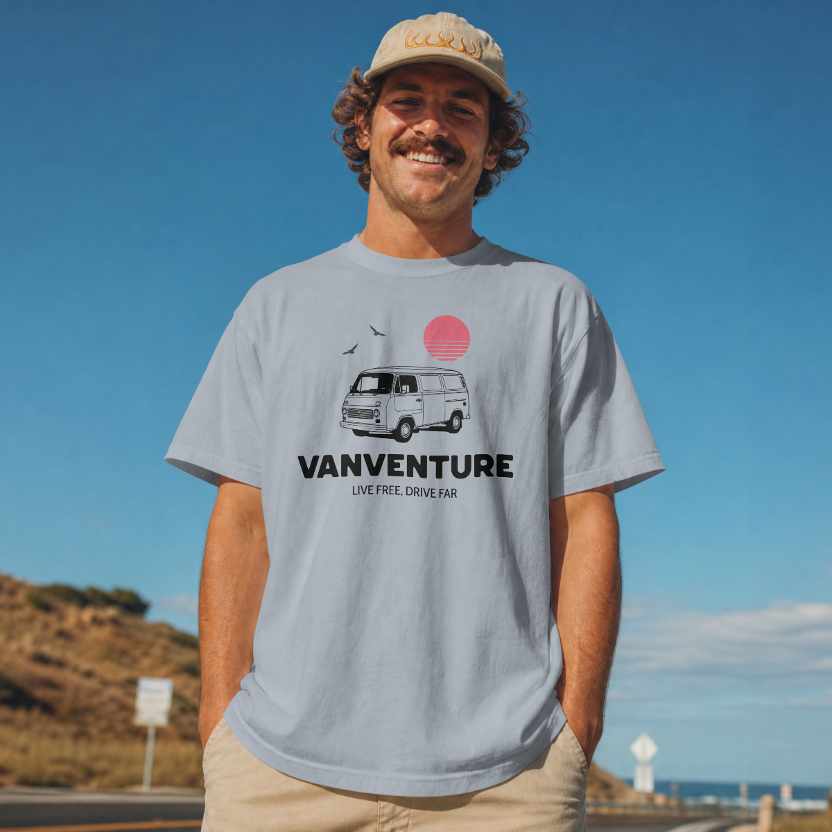 Man wearing a 'Vanventure' t-shirt with a van graphic against a blue sky.