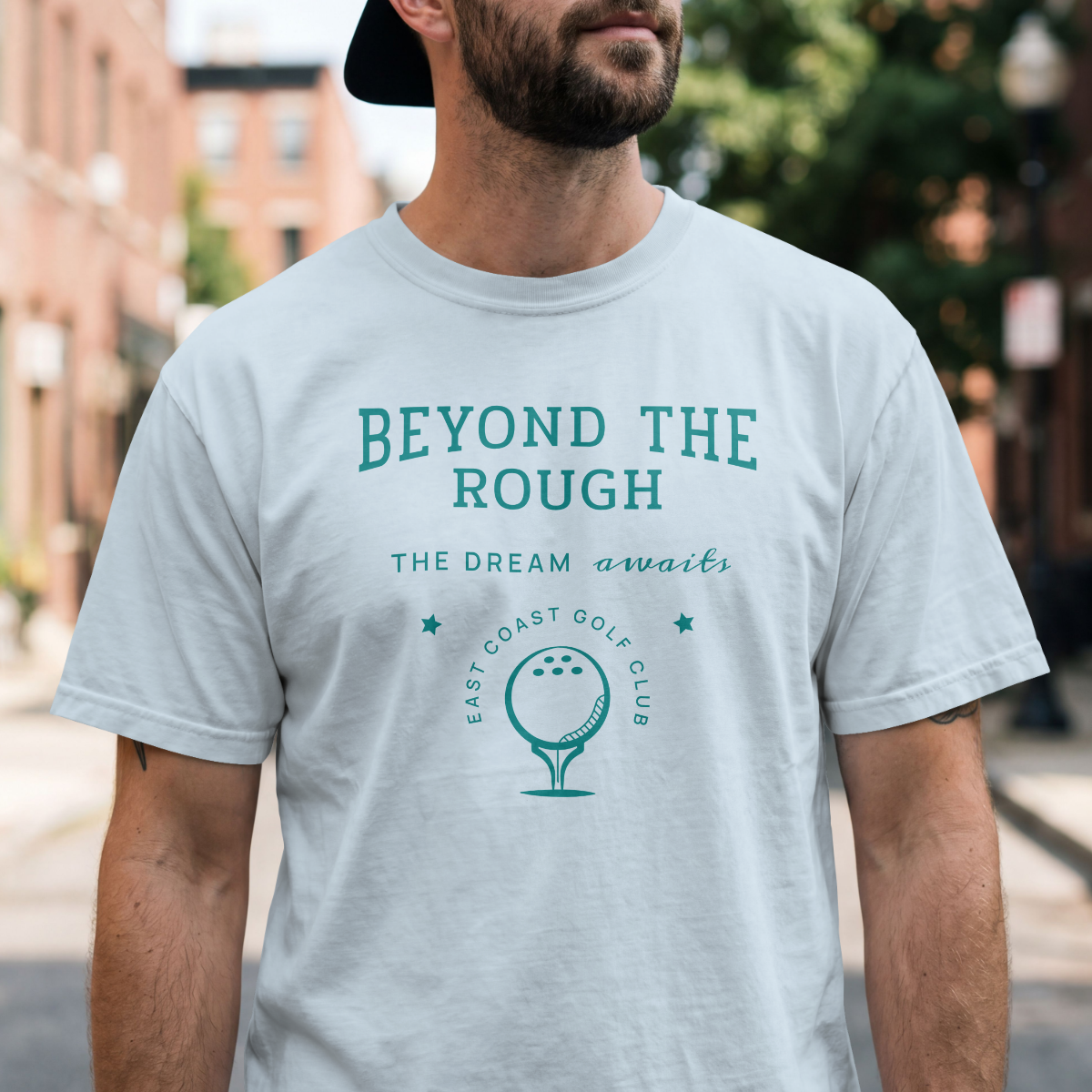 Man wearing light blue t-shirt with 'Beyond the Rough' text and golf graphic 