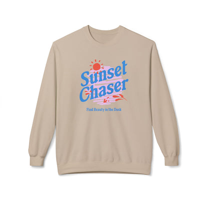 A beige crewneck sweatshirt featuring a retro-style graphic on the chest with the text 'Sunset Chaser' in blue, a red sun, and pink and blue stripes, with the phrase 'Find Beauty in the Dark' printed below.
