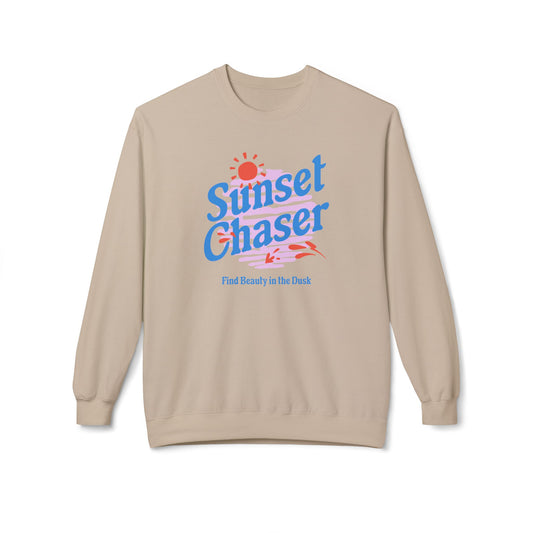 A beige crewneck sweatshirt featuring a retro-style graphic on the chest with the text 'Sunset Chaser' in blue, a red sun, and pink and blue stripes, with the phrase 'Find Beauty in the Dark' printed below.