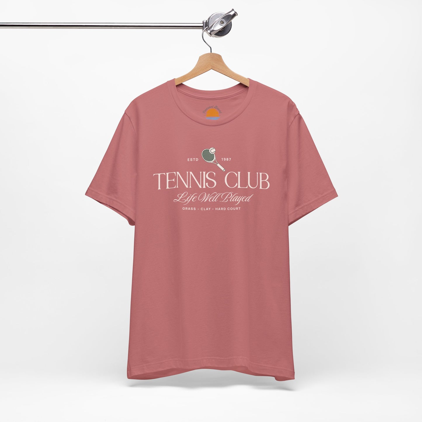 Mauve t-shirt with 'Tennis Club' text and graphics on a hanger against a white background