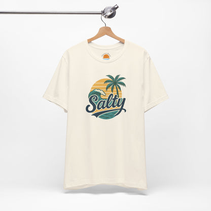 Beige t-shirt with 'Salty' graphic design featuring palm trees and a sunset on a hanger against a white background.