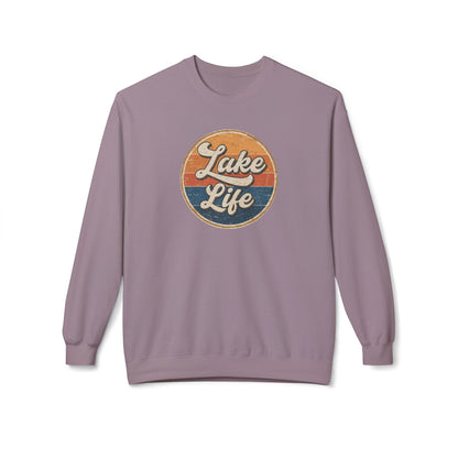 A dusty purple crewneck sweatshirt featuring a retro circular graphic on the chest with the text 'Lake Life' in white script over orange and blue sunset stripes.