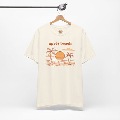 Natural color t-shirt with 'après beach' sunset and palm trees graphic design on a hanger against a white background.